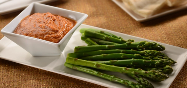 plate topped with asparagus next to a bowl of dip.