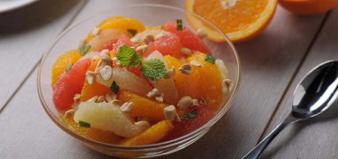 a bowl of fruit with nuts and oranges.