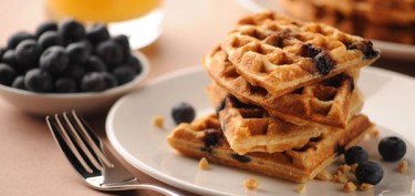 a stack of blueberry waffles and chunks of peanuts.