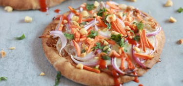 a flatbread topped with chopped carrots, peanuts and onions.
