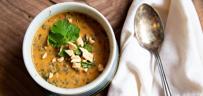 a bowl of stew with peanuts on top aof it.