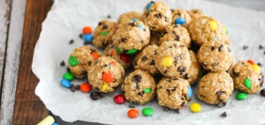a pile of cookies stuffed with chocolate chips and multi-colored candies.