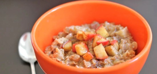 a close up of a bowl of oatmeal with apples.