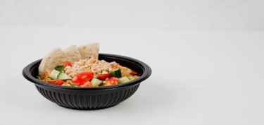 a plastic container full of nuts, vegetables and three pita bread slices.