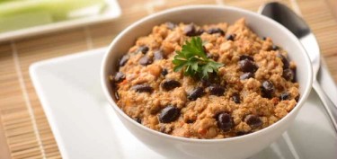 a chilli bowl with red beans and a cilantro leaf on top.