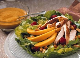 a plate topped with a salad covered in fruit and chicken.