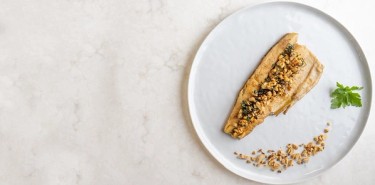 a single slice of fish topped with roasted peanuts and chopped parsley.