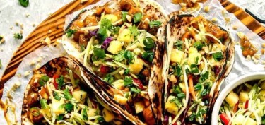 plate of tacos filled with diced chicken, vegetables and herbs.