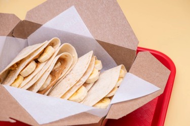 A delighful dish featuring a warm tortilla filled with creamy peanut butter, sliced bananas and a drizzle of honey.