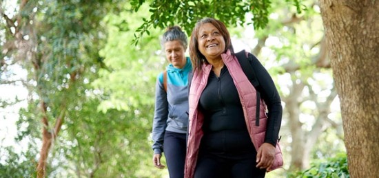 Two older women walking in a park.