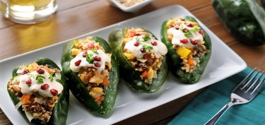 a plate of stuffed green peppers with meat and peanuts.