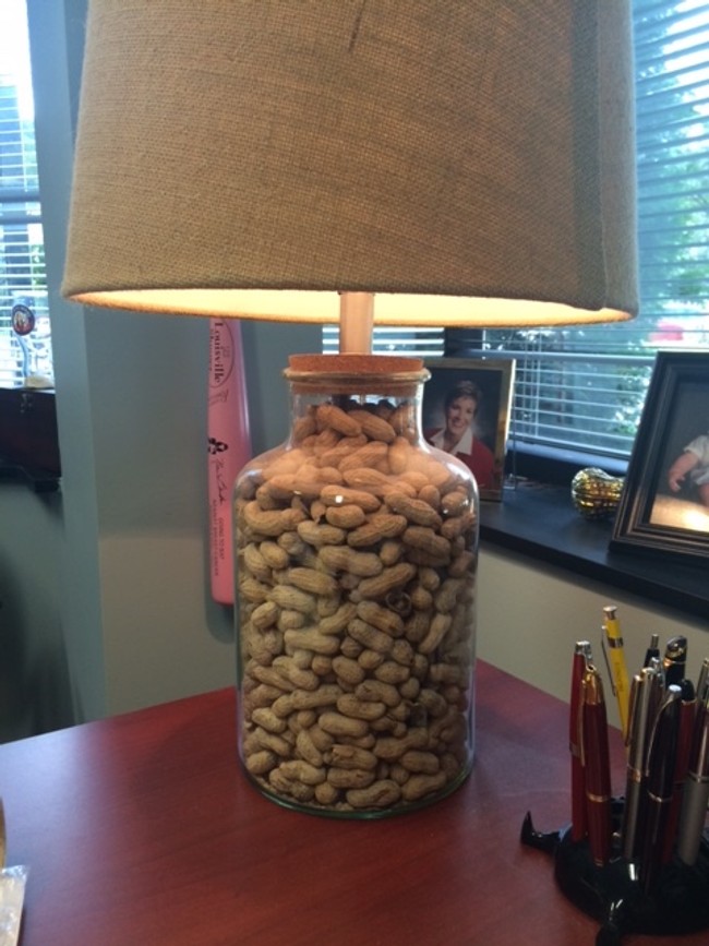 A lamp support made of glass filled with unshelled peanuts