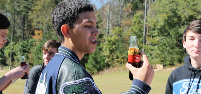 boy in a jacket holding a coke with peanuts