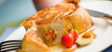 a french toast drizzled in honey, peanut butter and slices of banana and strawberries.