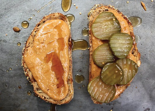two slices of bread topped with pickles, peanut butter and honey