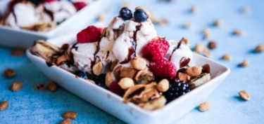 a bowl of ice cream with berries and nuts.