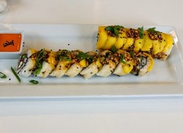 Rows of sushi topped with mango slices.