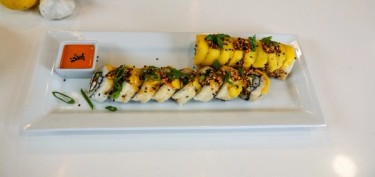 Rows of sushi topped with mango slices.