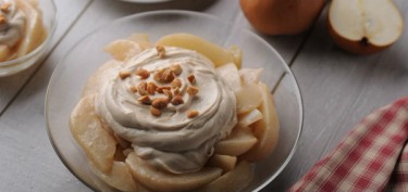 bowl full of pear slices topped with yogurt and pieces of peanuts.