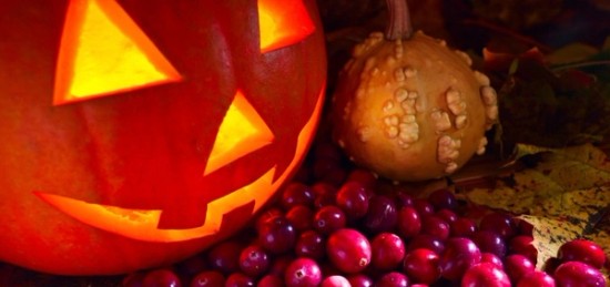 A jack o lantern surrounded by cranberries.