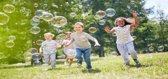 Children playing with soap bubbles in a park.