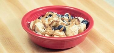 banana and blueberries drizzled with peanut butter in a bowl.
