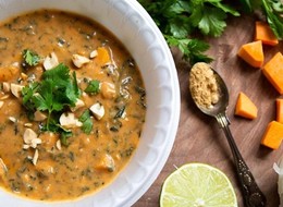 a bowl full of stew topped with herbs and peanuts.