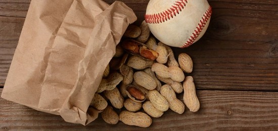 a bag of peanuts and a baseball ball on a wooden table.