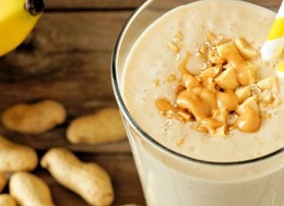 a cup filled with banana and peanuts smoothie with two straws popping out.