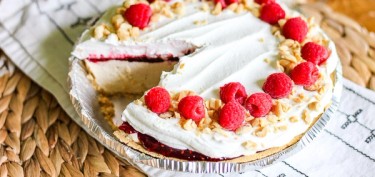 a pie with white frosting and raspberries on top.