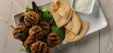 a plate topped with grilled kebabs and pita bread.