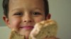 A young boy is holding up a piece of bread.