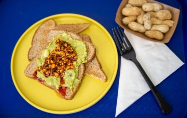 A vibrant dish that combines creamy avocado spread on toasted bread, topped with a spicy and crunch salsa.