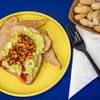 A vibrant dish that combines creamy avocado spread on toasted bread, topped with a spicy and crunch salsa.