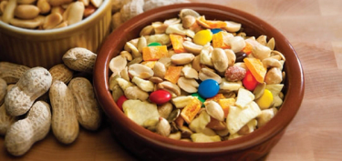 a bowl filled with dry fruits, peanuts and skittles.