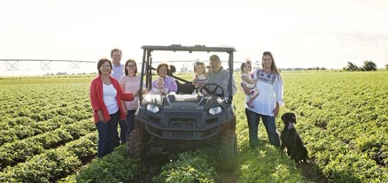 peanut farmer Gayle White and her family standing in a field next to a tractor.