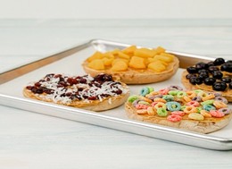 a tray with four cookies topped with cereal and dry fruits.