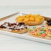 a tray with four cookies topped with cereal and dry fruits.