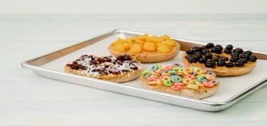 a tray with four cookies topped with cereal and dry fruits.