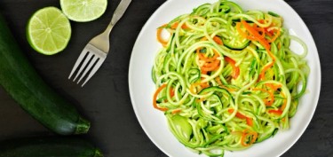 a plate of zucchini noodles with carrots and green peppers.