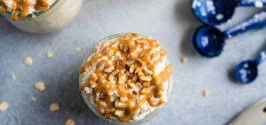 top view of a glass with oatmeal topped with peanuts bits and peanut butter.