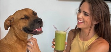 a girl sharing her smoothie with her dog
