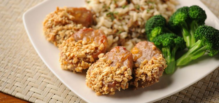 slices of pork in a plate with rice and brocolli.