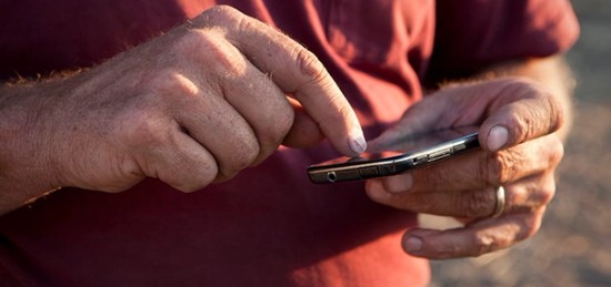 an old man typing in a smartphone.