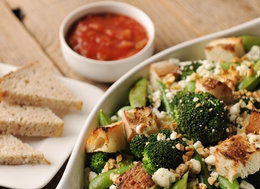 a bowl of broccoli, cauliflower, and bread on a table.