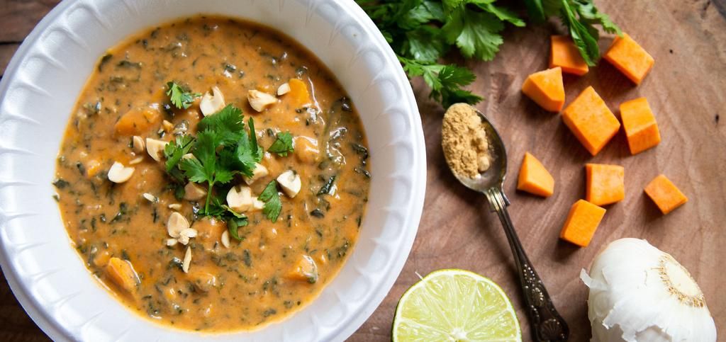 a bowl full of stew topped with herbs and peanuts.