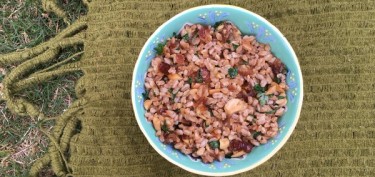 bowl of nuts and dry fruits on top of a green tablecloth.