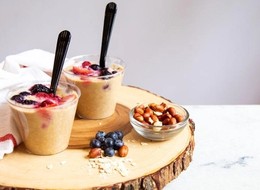 two cups full of oatmeal topped with fresh berries.