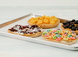 a tray with four cookies topped with cereal and dry fruits.