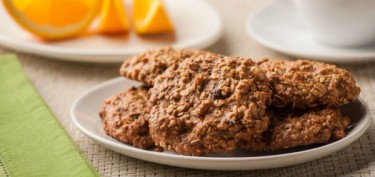 peanut crusted cookies next to a plate of sliced oranges.